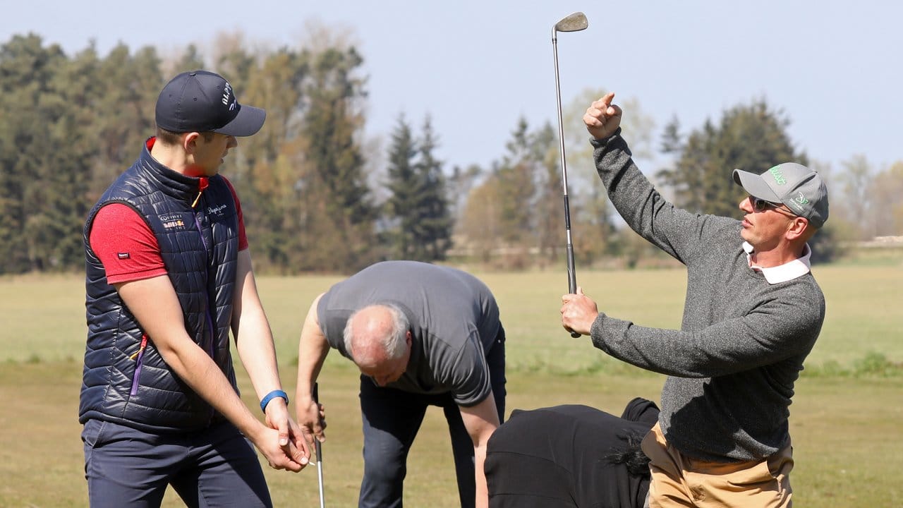 Golflehrer Tom Siegfried (r) zeigt seinem Schüler Jonathan Dommermuth (l) den richtigen Abschlag.