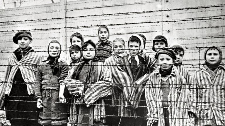 Überlebende jüdische Kinder in Auschwitz Mit Krankenschwester hinter Stacheldrahtzaun Das Foto wurd