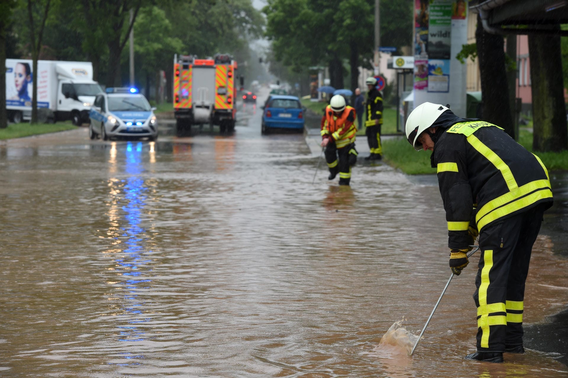 Kassel am Dienstag: Feuerwehrleute suchen mit Eisenstangen in einer überfluteten Straße nach dem Gullydeckel. Schwere Regenfälle haben die Bäche im Kasseler Osten zum Überlaufen gebracht.