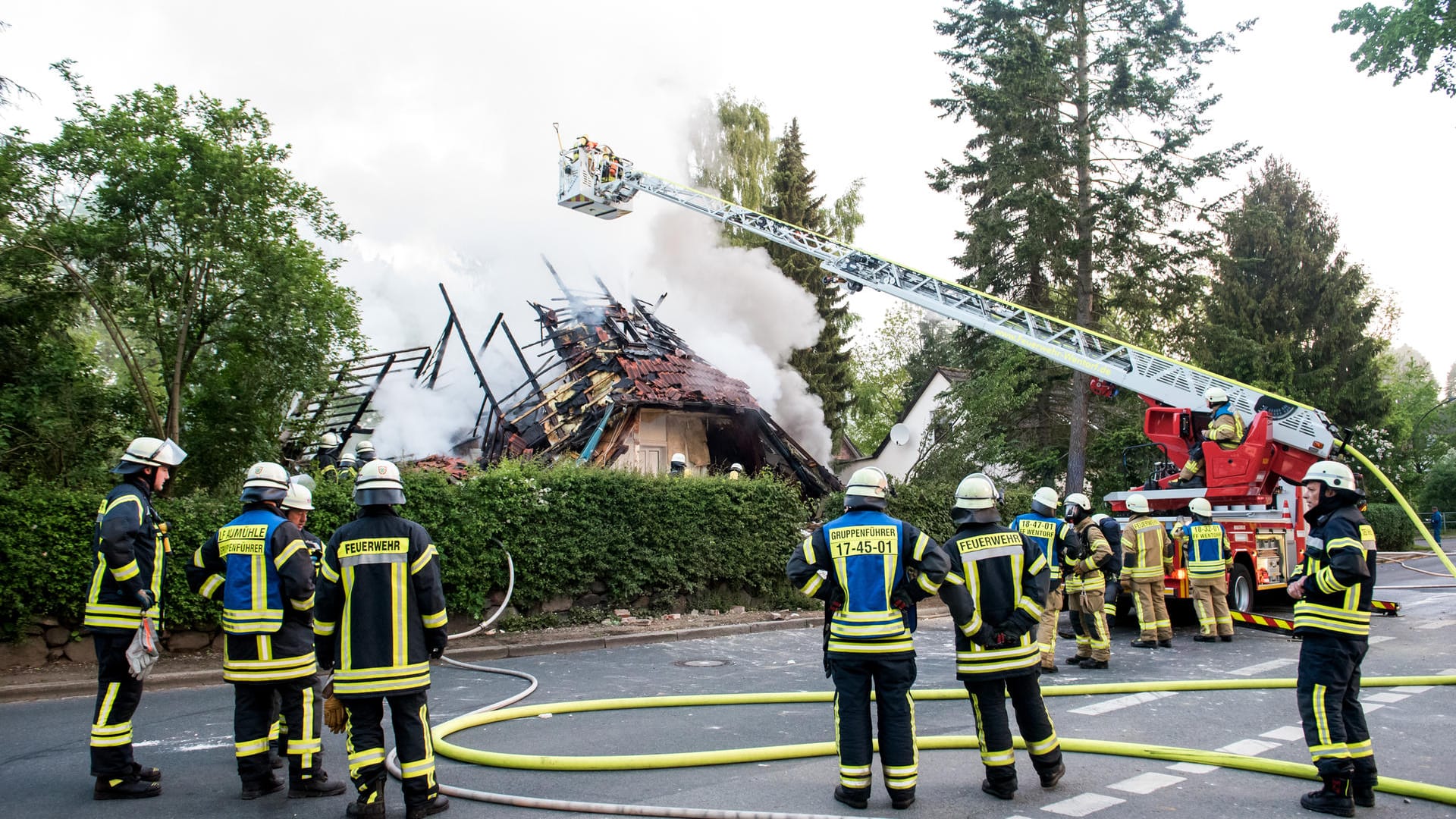 Feuerwehrleute stehen vor den Trümmern eines Wohnhauses, das bei einem Brand zerstört wurde.