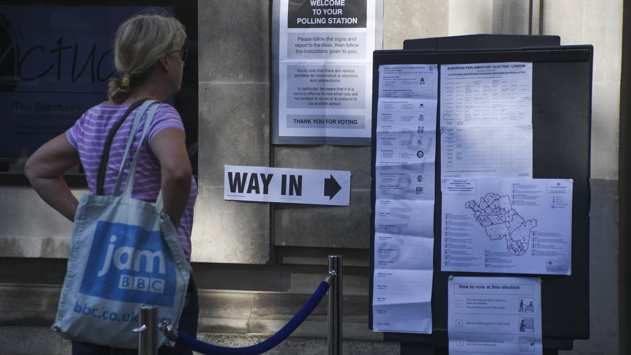 Eine Frau steht in London vor einem Wahllokal.