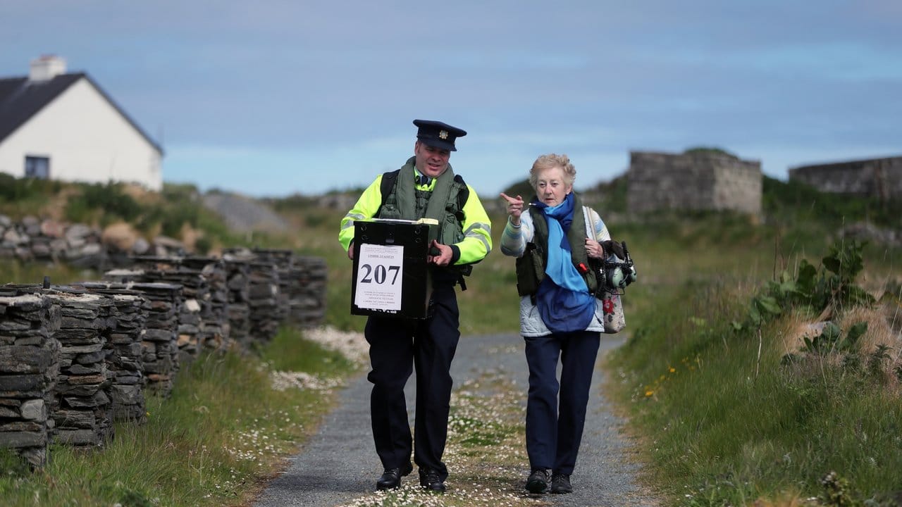 Carmel McBride (r) und Garda Adrian McGettigan tragen eine Wahlurne zu einem Wahllokal auf der Insel Inishbofin.