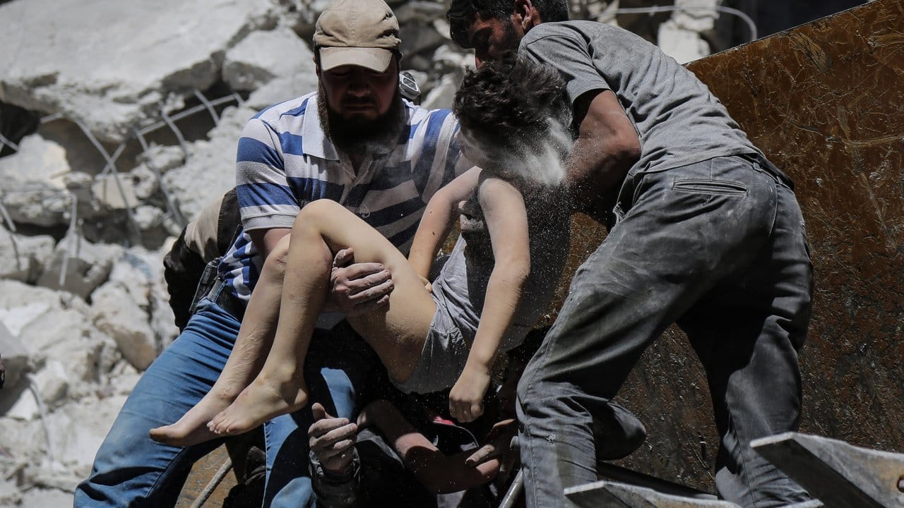 Mitglieder der syrischen Weißhelme und Freiwillige retten ein verletztes Kind aus den Trümmern eines Gebäudes, das bei einem Luftangriff durch die syrischen Regierungskräfte beschädigt wurde.