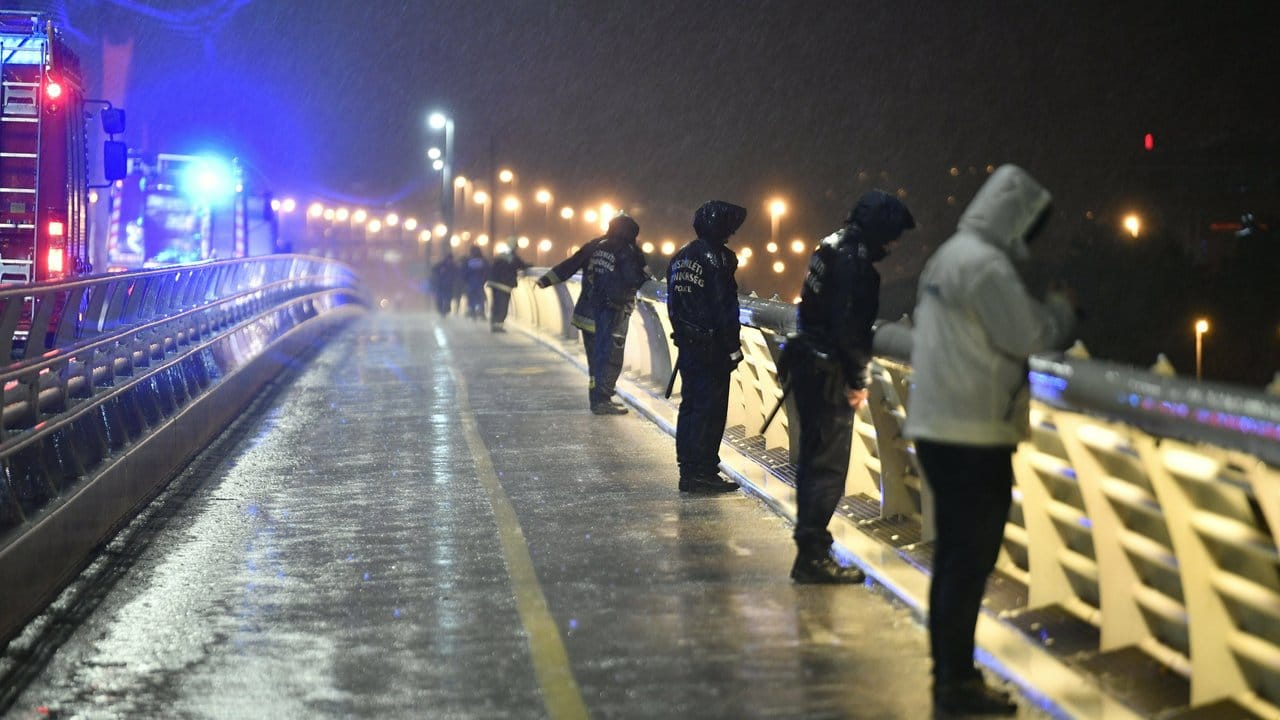 Rettungskräfte und Polizisten inspizieren die Donau von einem Anlegesteg aus.