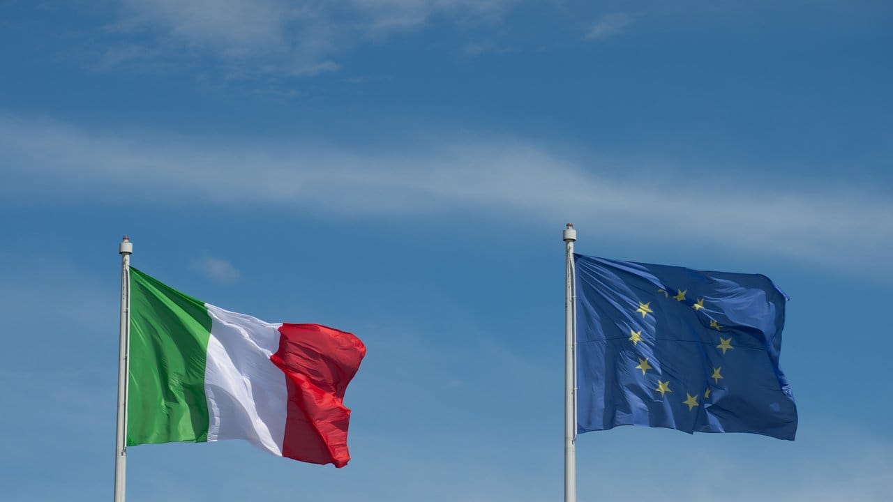 Die Flaggen der EU und Italiens: Die EU-Kommission empfiehlt ein Strafverfahren gegen das Land.