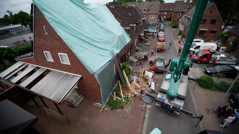 Das beschädigte Dach eines Hauses wird von einer Plane bedeckt und so vor möglichem Regen geschützt.