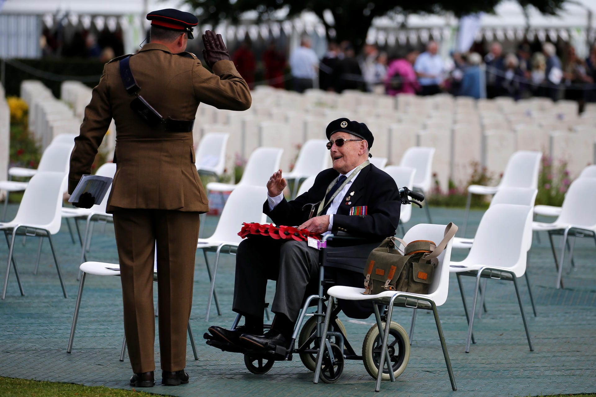 Ein Soldat salutiert auf dem englischen Soldatenfriedhof in Bayeux vor einem D-Day-Veteranen.