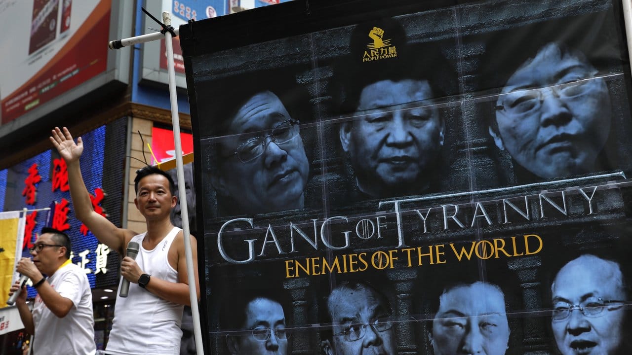 Demonstranten halten ein Banner, auf dem unter anderem der chinesische Präsident Xi (M) zu sehen ist, mit der Aufschrift "Game of Tyranny - Enemies of the World".