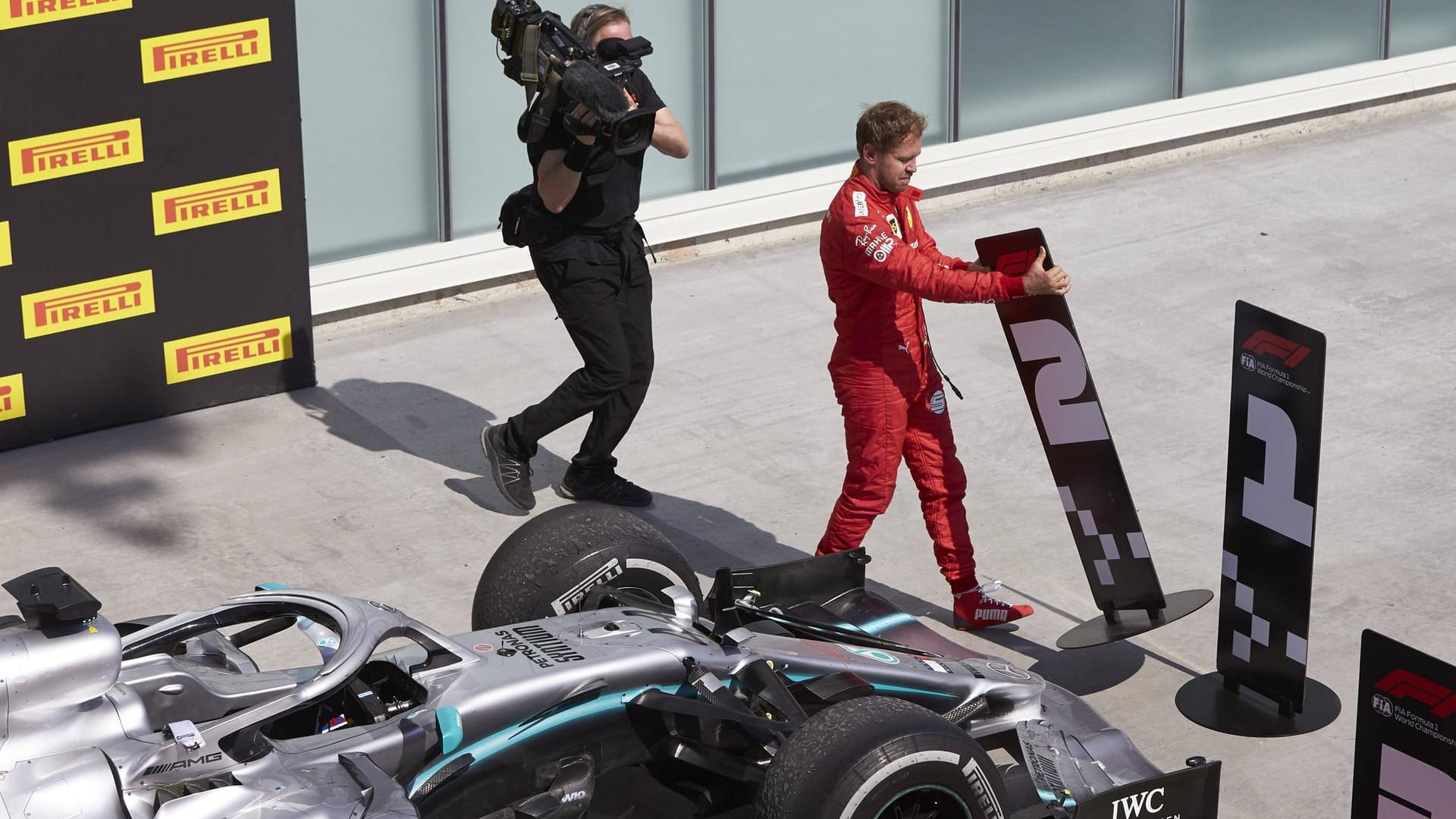 Nach dem Rennen fuhr ein angefressener Sebastian Vettel seinen Wagen nicht zur Nummer. Damit standen die Boliden von Lewis Hamilton und Charles Leclerc alleine da. Tatenlos blieb Vettel aber nicht. Er stapfte zu den Schildern, nahm sich seine 2...