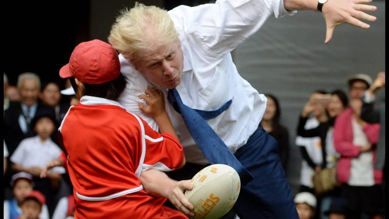 Nicht zu stoppen: Boris Johnson rennt bei einem kurzen Rugbyspiel mit Schülern in Tokio den 10-jährigen Toki Sekiguchi um.