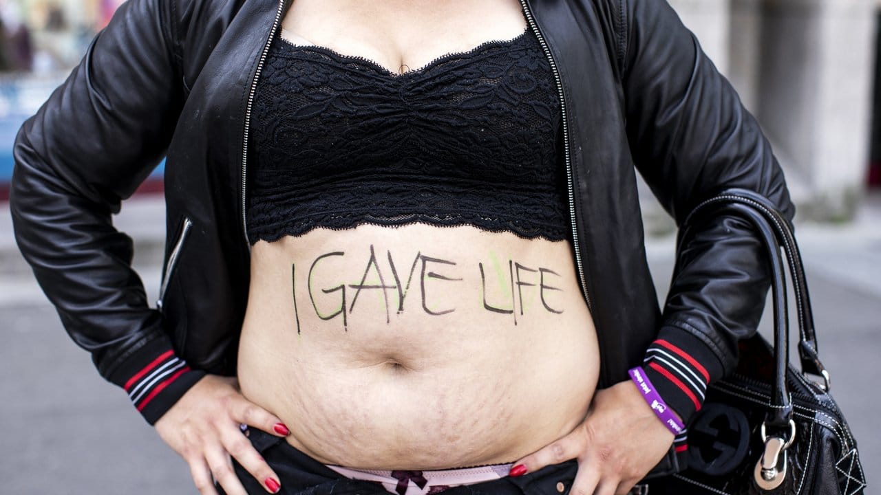 Eine Frau zeigt ihren Bauch mit der Aufschrift "I gave life" ("Ich habe Leben gegeben").
