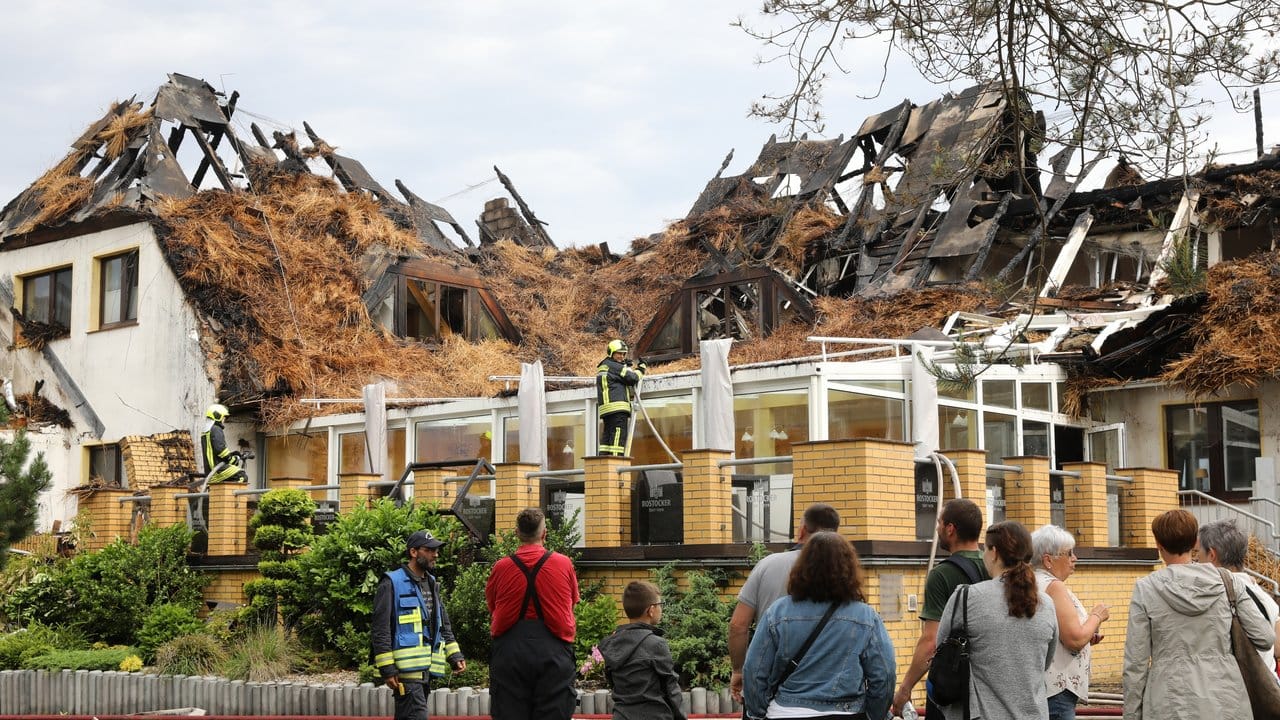 Urlauber und Feuerwehrleute stehen vor dem ausgebrannten Ostseehotel auf der Halbinsel Fischland-Darß-Zingst. Urlauber und Feuerwehrleute stehen vor dem ausgebrannten Ostseehotel auf der Halbinsel Fischland-Darß-Zingst.