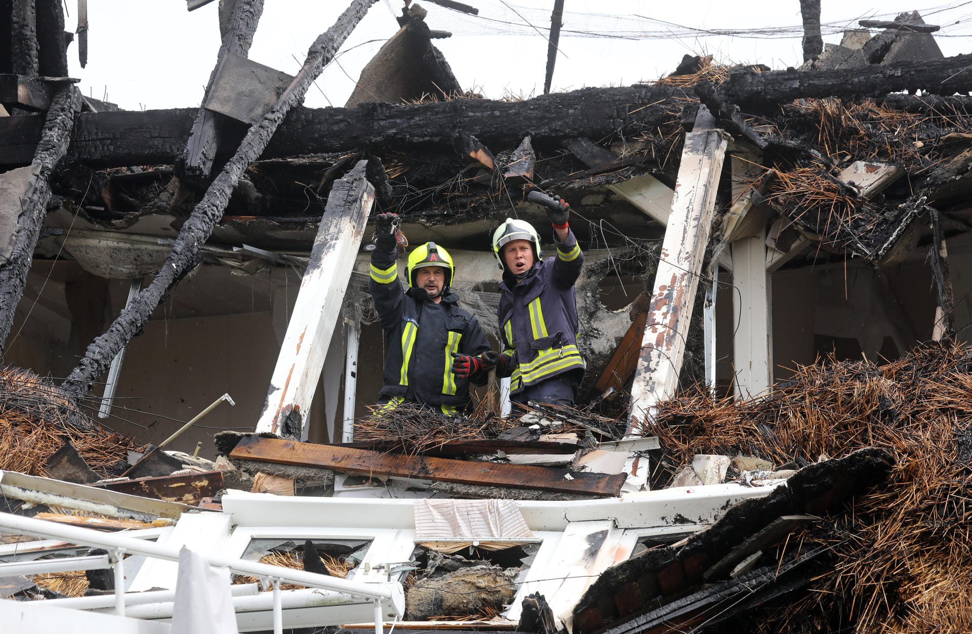 Zwei Feuerwehrmänner stehen im Dachstuhl des ausgebrannten Hotels