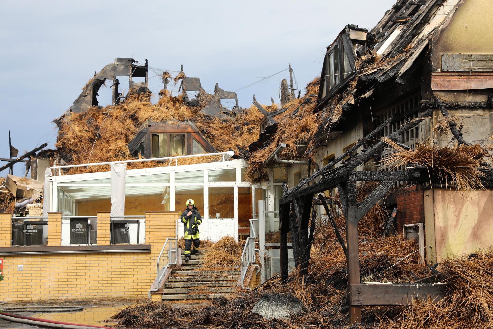 Feuerwehrmann steht am niedergebrannten Ostseehotel