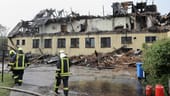 Einsatzkräfte stehen vor einem ausgebrannten Hotel an der Ostseean der Ostsee