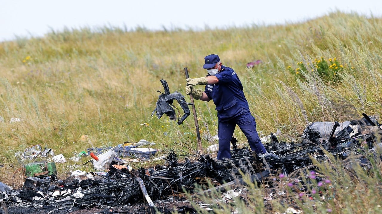 Ein ukrainischer Arbeiter untersucht im Juli 2014 an der Absturzstelle von MH17 Wrackteile der Maschine.