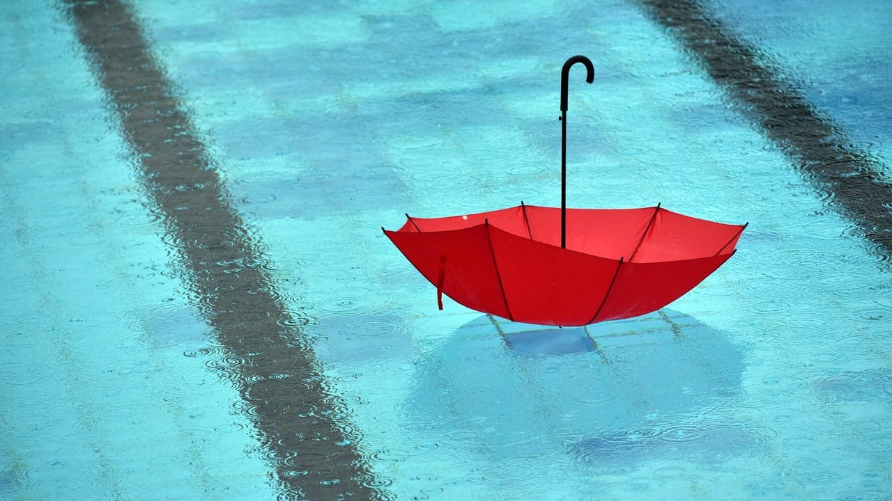 Bei Regen schwimmt ein Regenschirm im Freibad. Bei Regen schwimmt ein Regenschirm im Freibad.