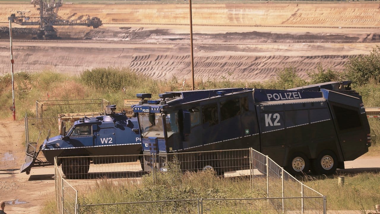 Ein gepanzertes Räumfahrzeug und ein Wasserwerfer der Polizei stehen am Rand des Braunkohle-Tagebaus Garzweiler.