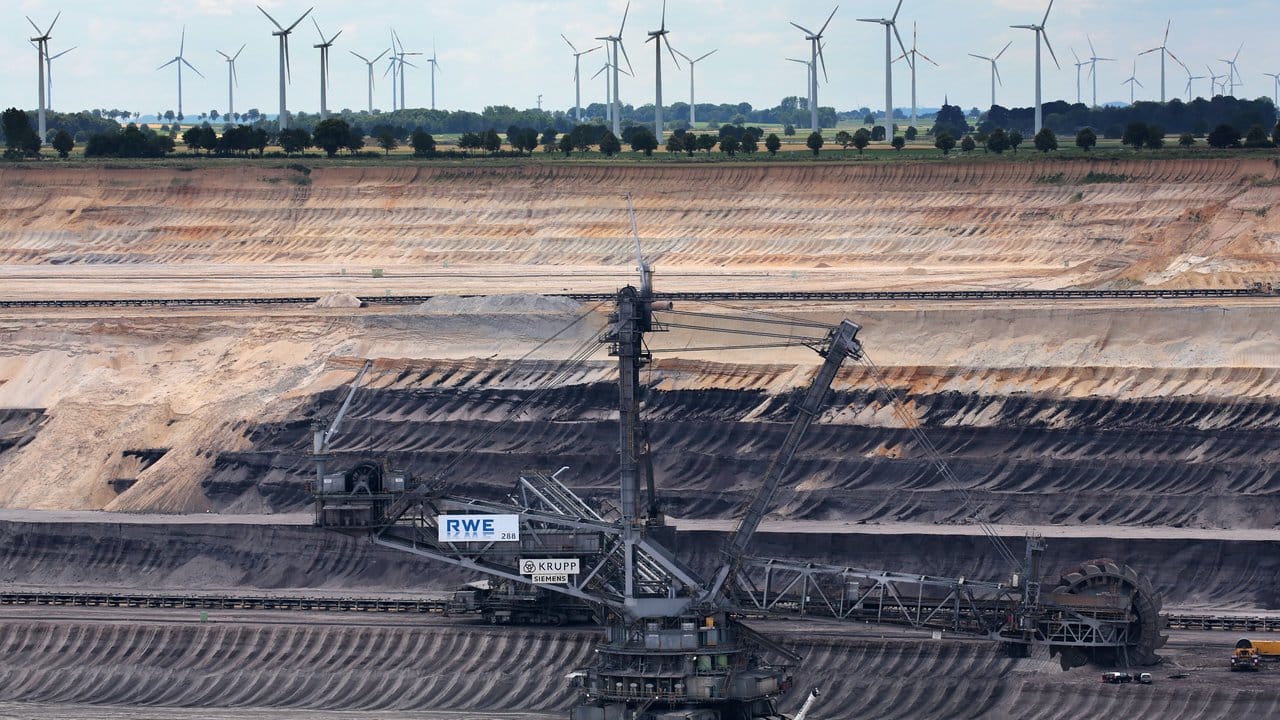 Braunkohlebagger im Tagebau Garzweiler, dahinter sind Windräder zu sehen.