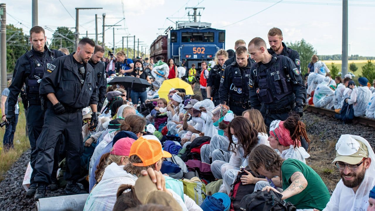 Unter Polizeibeobachtung aus nächster Nähe: Aktivisten blockieren am Freitag die Gleise der Kohle-Transportbahn.