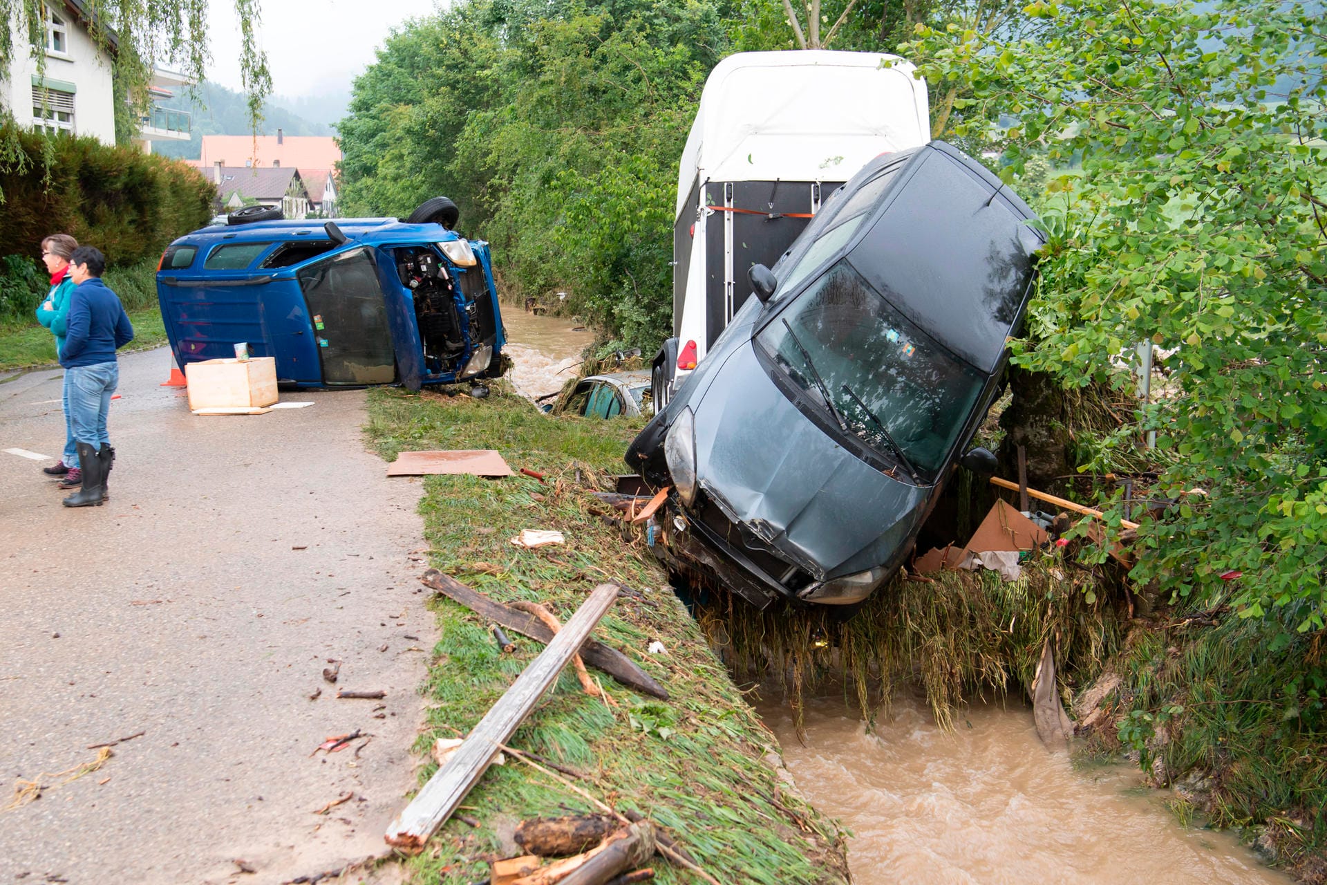 In der Schweiz wurden bei starken Unwettern Autos von einem angeschwollenen Fluss mitgerissen und liegen nun umgestürzt am Flussufer.