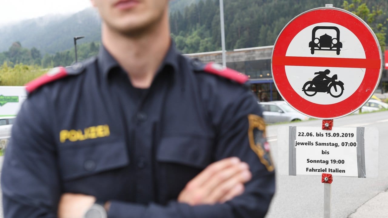 Ein Polizist vor einem Schild, das auf die Sperrung für den Verkehr mit Fahrziel Italien hinweißt.