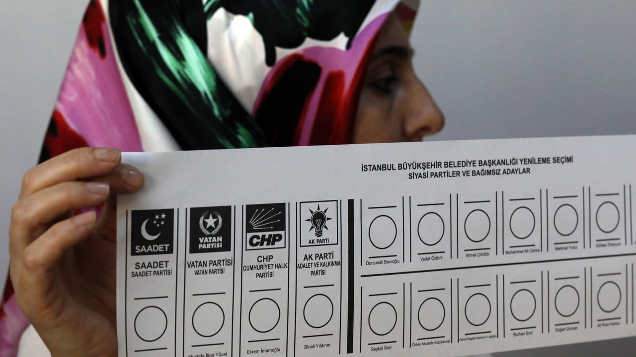 Eine Wahlhelferin hält in einem Wahllokal in Istanbul einen Stimmzettel in der Hand.
