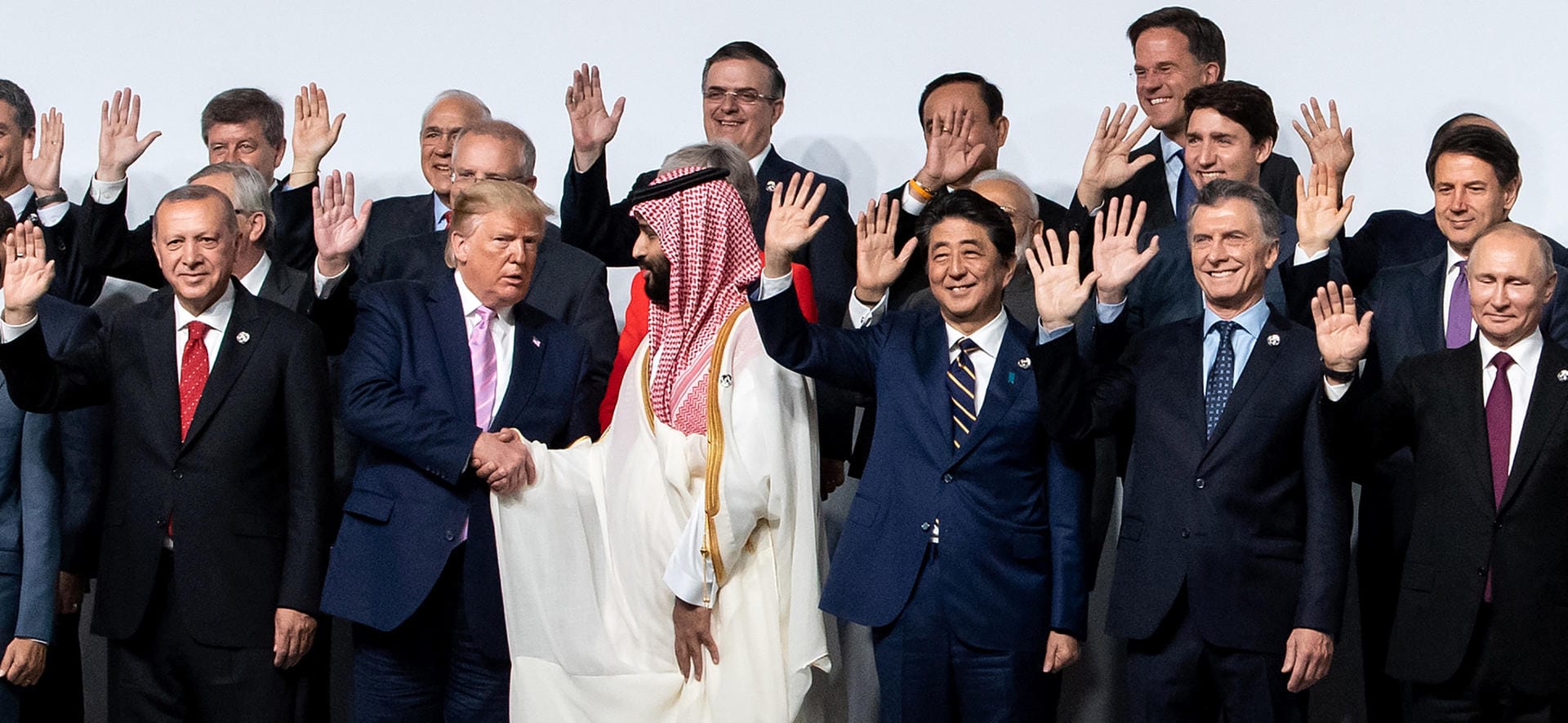 Er gilt als Mitwisser des Auftragsmordes an Jamal Khashoggi: Saudi-Arabiens Kronprinz Mohammed bin Salman. Dass er beim G20-Gipfel ausgerechnet in der ersten Reihe steht, hat allerdings protokollarische Gründe: Denn der Saudi ist Gastgeber des nächsten Gipfels. Demonstrativ hingegen scheint Trumps Händeschüttel-Geste, wo alle anderen schon winken. Der US-Präsident braucht den Prinzen als Verbündeten gegen den Iran.