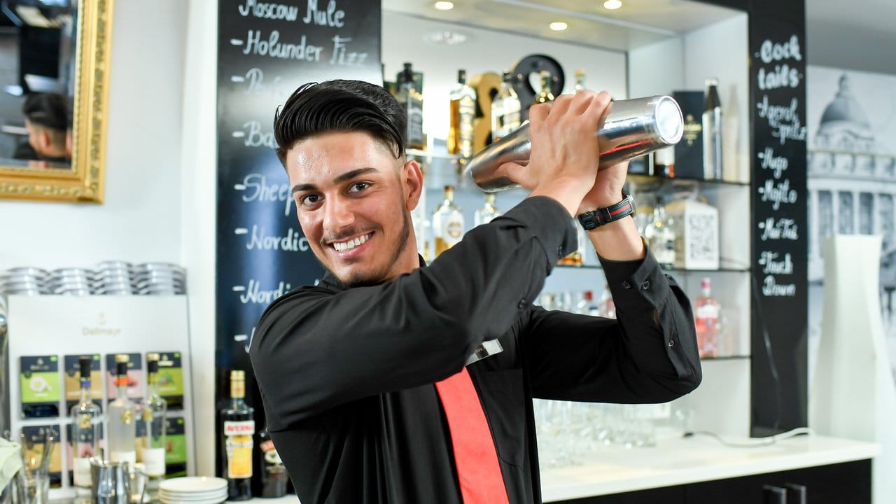Die Ausbildung zur Fachkraft im Gastgewerbe umfasst die Bereiche Service, Hauswirtschaft und Küche: Azubi Ishaq Shabak Khel mixt an der Bar seines Ausbildungsbetriebs, dem Victor’s Residenz-Hotel in Unterschleißheim bei München, einen Cocktail mit dem Shaker.