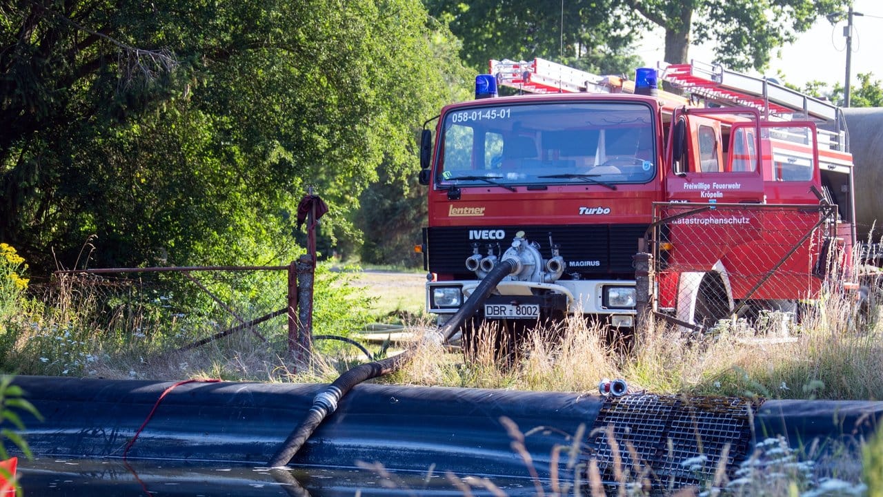 Feuerwehrleute pumpen Wasser aus einem Löschteich. Feuerwehrleute pumpen Wasser aus einem Löschteich.