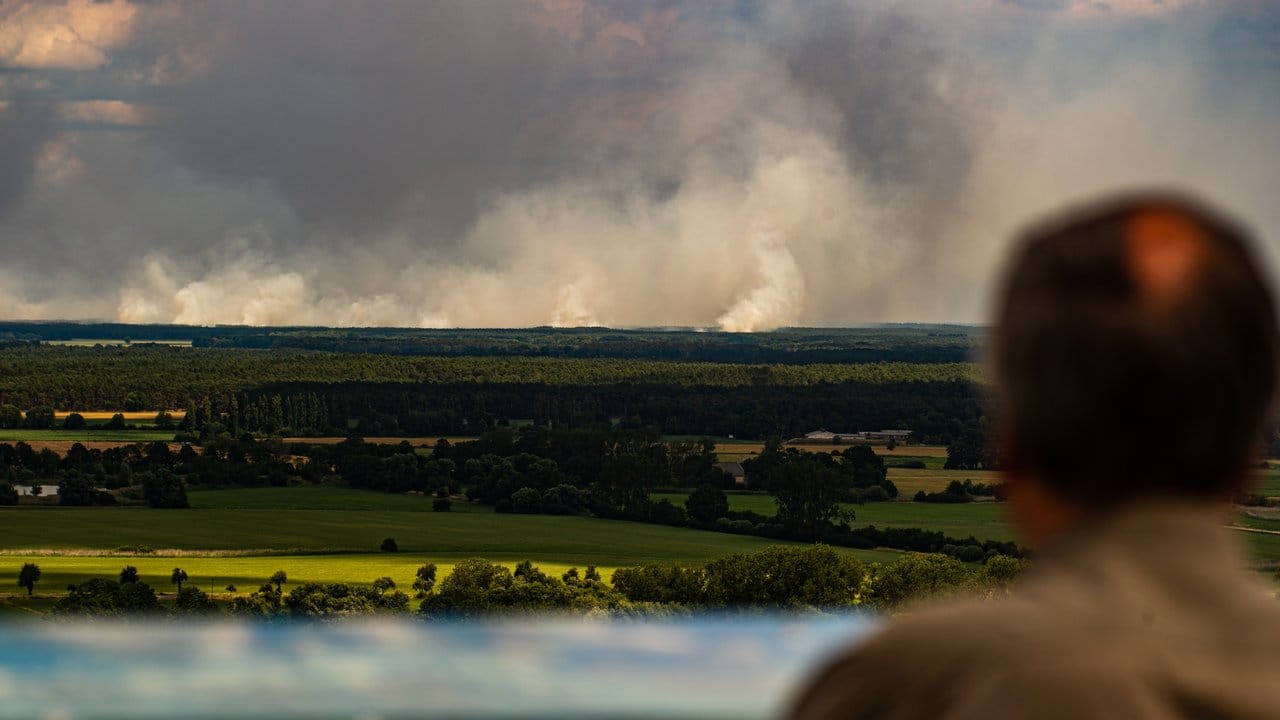 Ein Mann blickt von einem Aussichtsturm von Niedersachsen aus über die Elbe auf den Waldbrand bei Lübtheen in Mecklenburg-Vorpommern. Ein Mann blickt von einem Aussichtsturm von Niedersachsen aus über die Elbe auf den Waldbrand bei Lübtheen in Mecklenburg-Vorpommern.