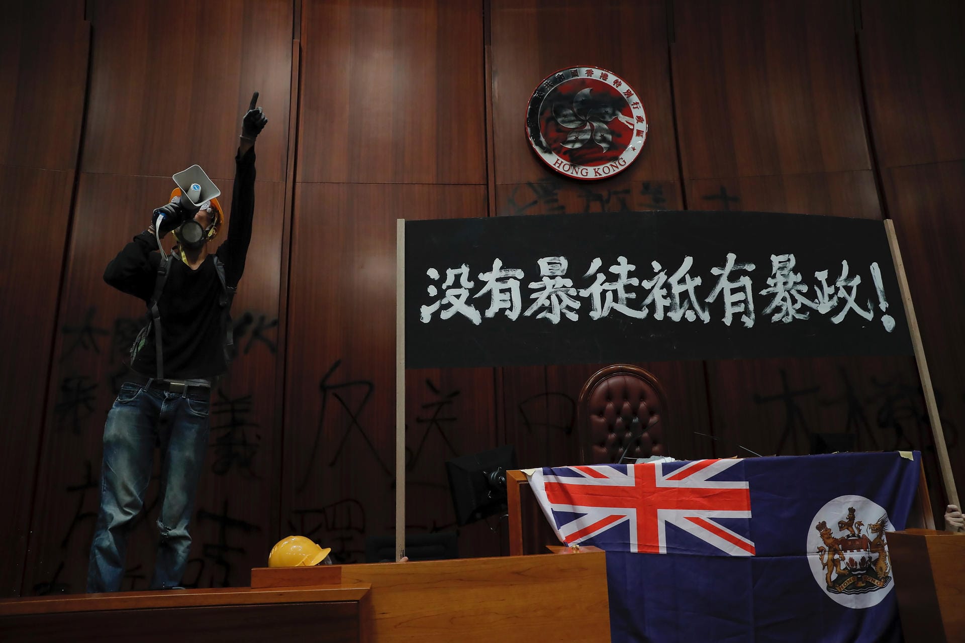 Besprühte Wände: Ein Demonstrant steht mit Megafon im Legislative Council, dem Parlament in Hongkong, vor vollgesprühten Wänden mit Forderungen an die Regierung.