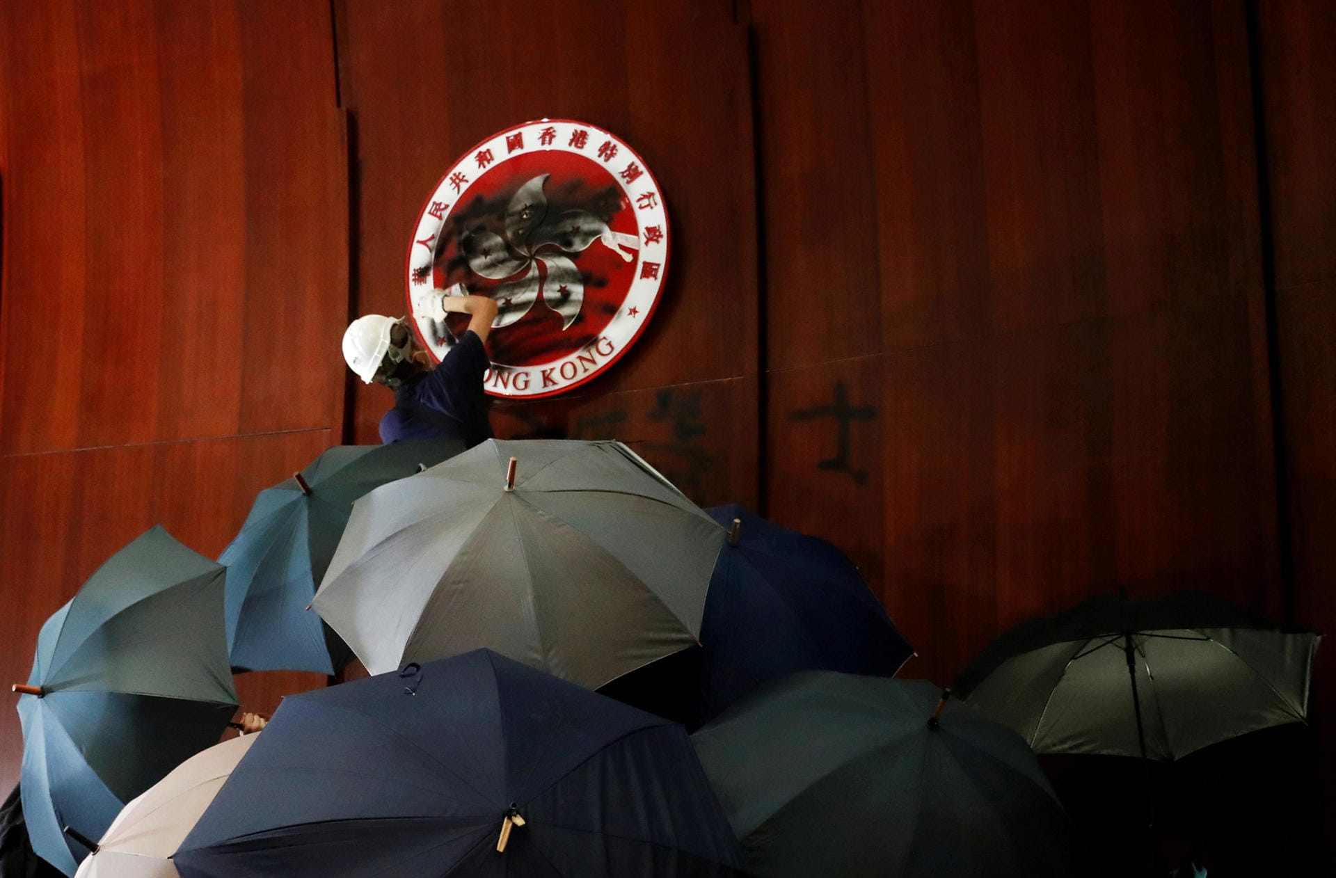 Demonstrant übersprüht das Wappen Hongkongs im Parlament: Am Jahrestag der Übergabe des Stadtstaats von Großbritannien an China sind die Proteste eskaliert.