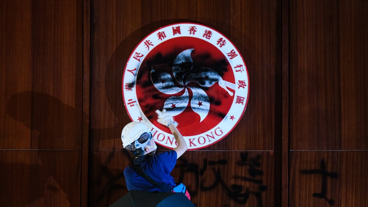 Im Hongkonger Parlament, dem Gebäude des Legislativrats, schwärzt ein Demonstrant das Emblem der Stadt.