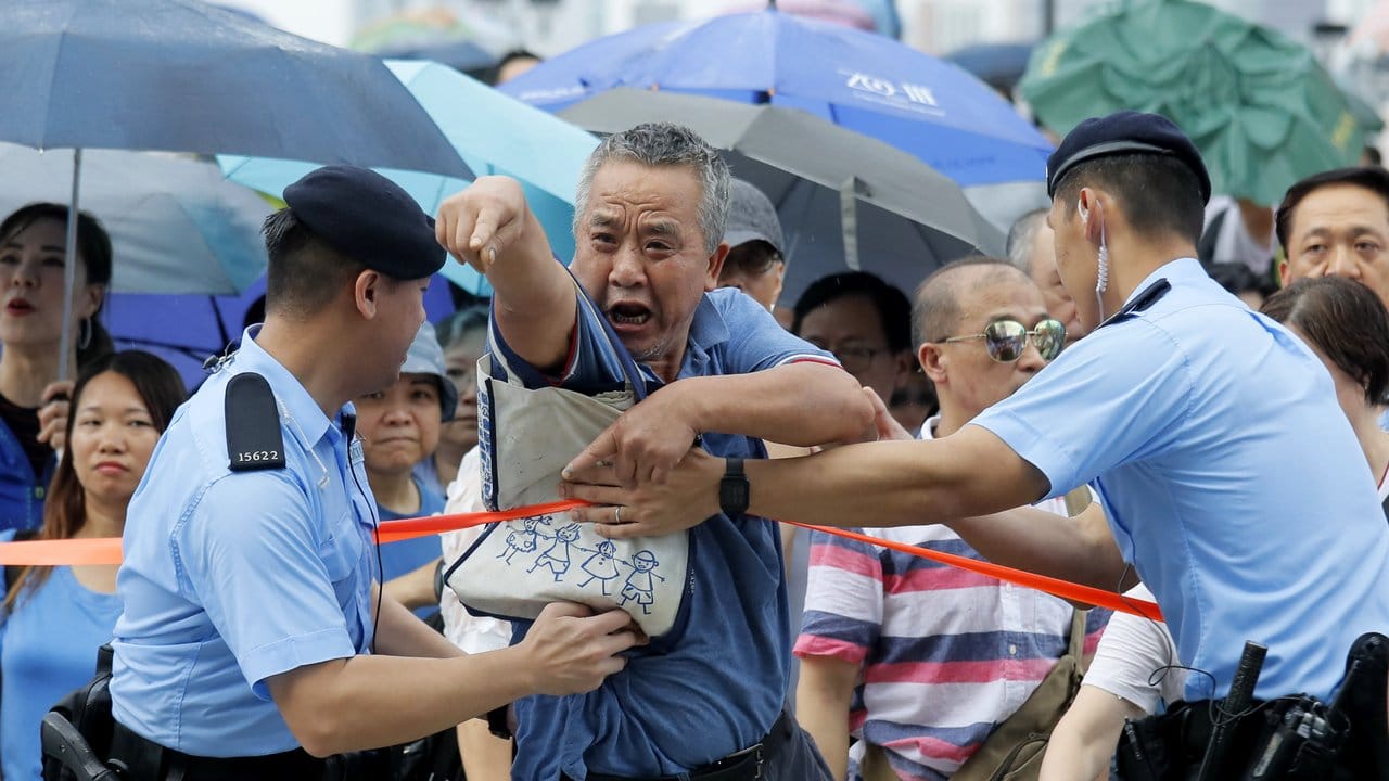 Gegenprotest: Ein pro-chinesischer Demonstrant wird während einer Kundgebung von Polizisten zurückgehalten.