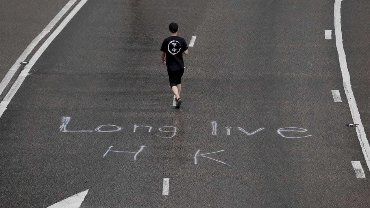 Ein Demonstrant auf einer Straße, auf der "Long live HK" (Lang lebe Hongkong) steht.