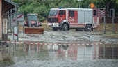 Ein Traktor und ein Feuerwehrauto stehen in den verwüsteten Straßen: Die Aufräumarbeiten in Uttendorf beginnen Dienstagfrüh.