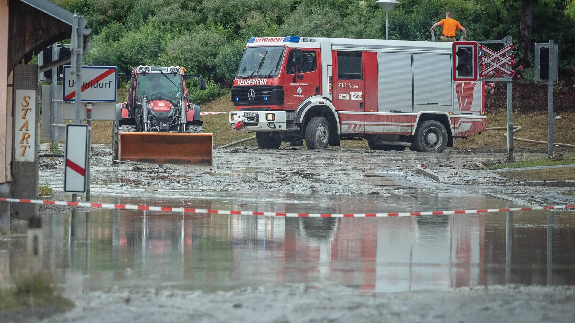 Ein Traktor und ein Feuerwehrauto stehen in den verwüsteten Straßen: Die Aufräumarbeiten in Uttendorf beginnen Dienstagfrüh.