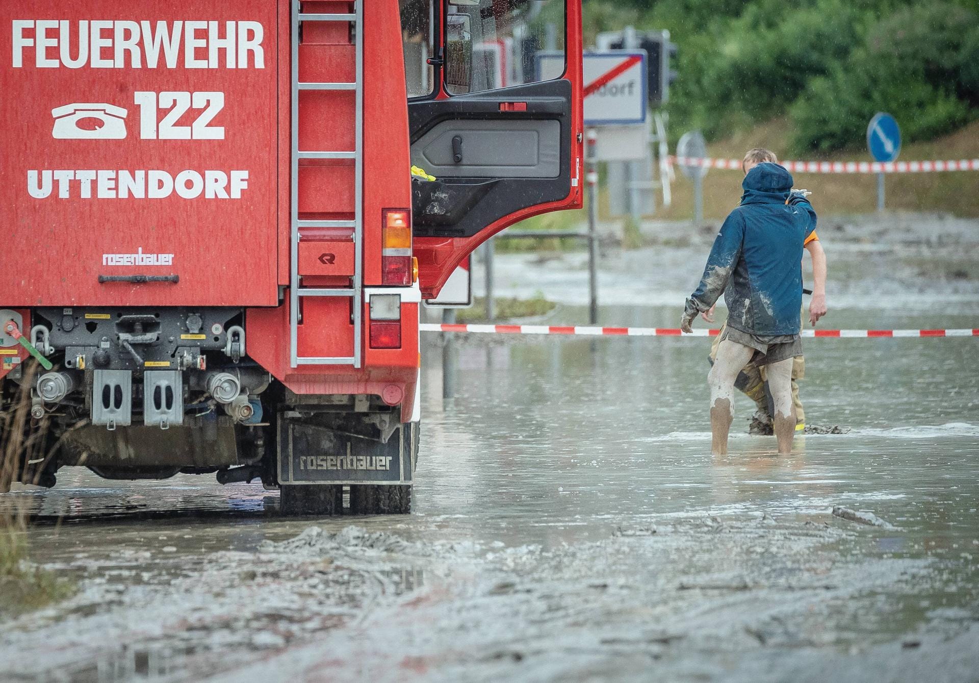 Zwei Männer stehen bis zu den Knien in dem Schlammwasser. Der Feuerwehr gelang es, bis zum späten Montagabend alle Bewohner aus ihren Häusern zu befreien.