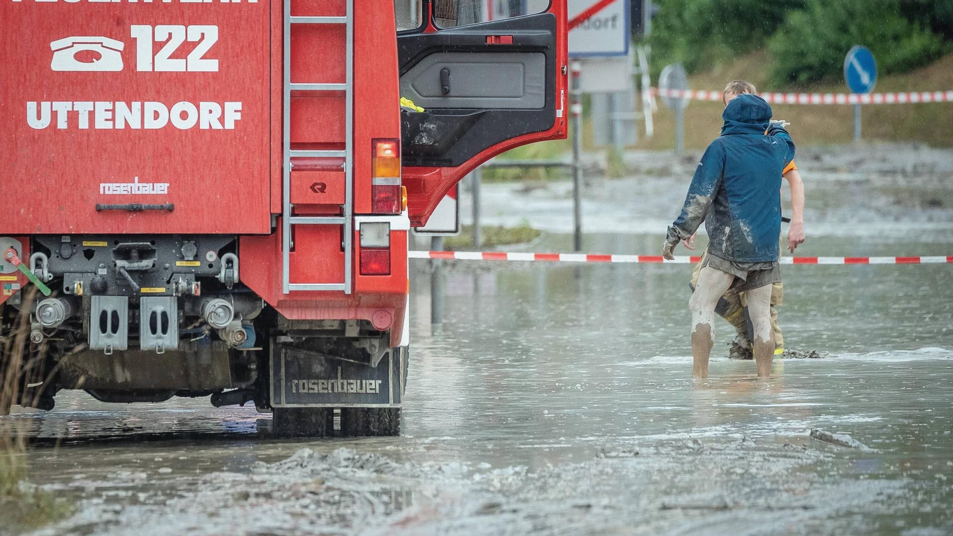 Zwei Männer stehen bis zu den Knien in dem Schlammwasser. Der Feuerwehr gelang es, bis zum späten Montagabend alle Bewohner aus ihren Häusern zu befreien.