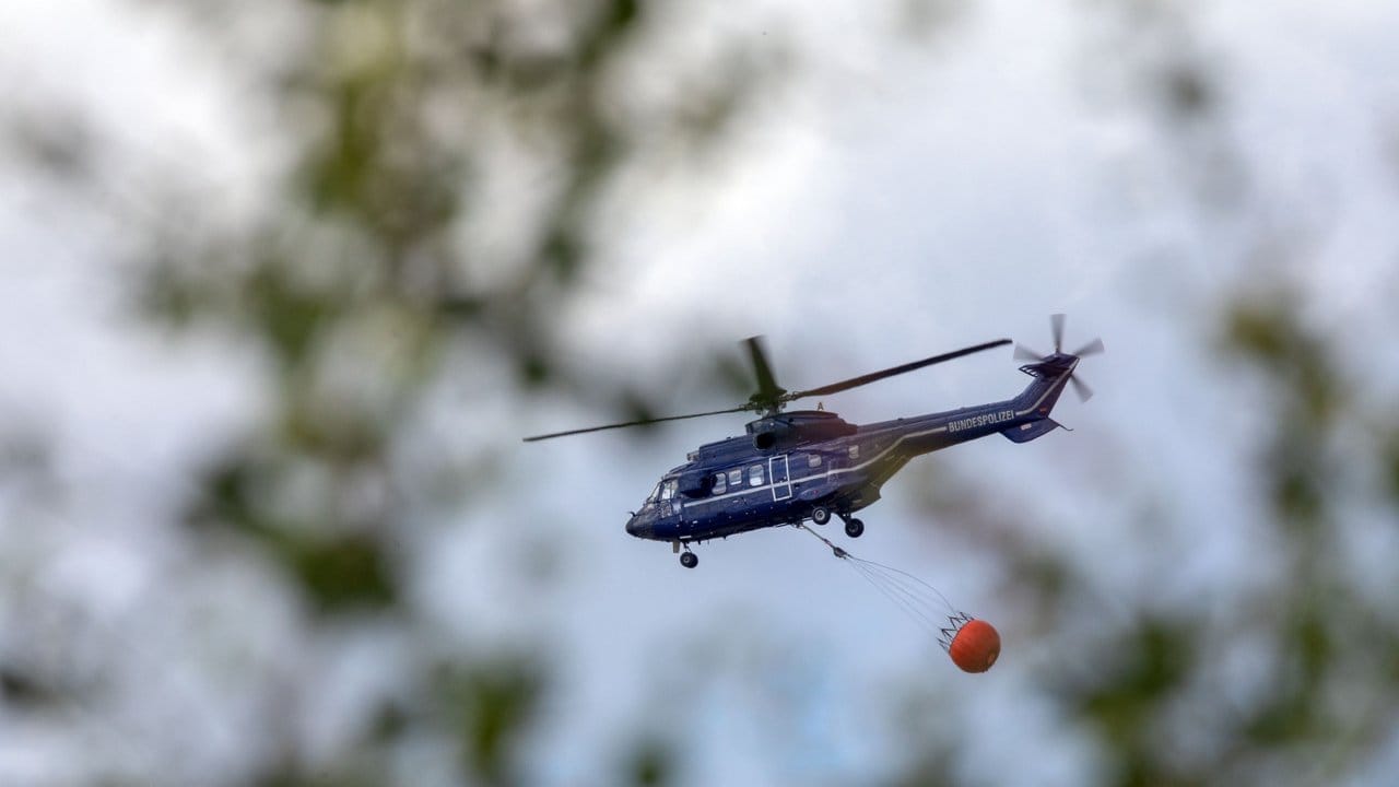 Ein Hubschrauber der Bundespolizei transportiert Löschwasser zu einem Brandherd.
