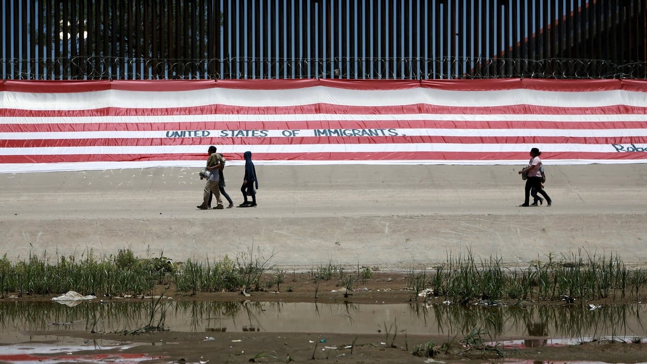 Migranten gehen in Ciudad Juarez in Mexiko an einem Grenzzaun vorüber.