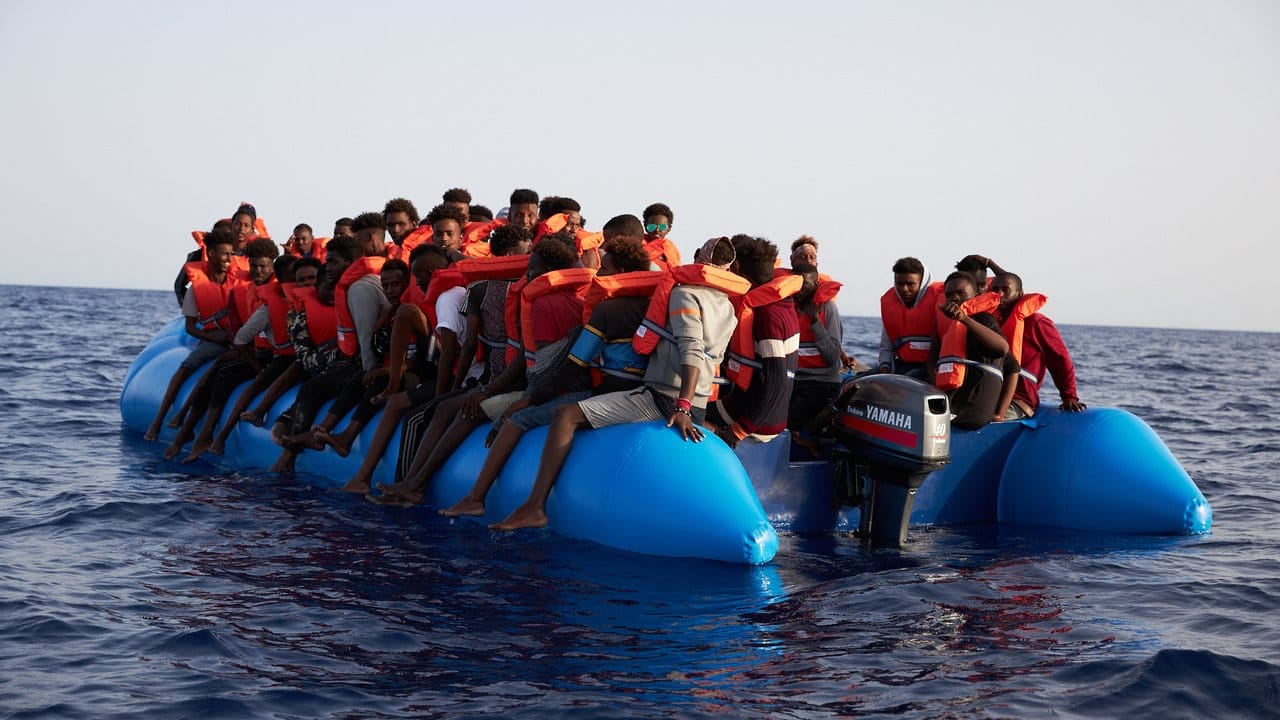 Flüchtlinge sitzen vor der Küste von Libyen in einem Schlauchboot.