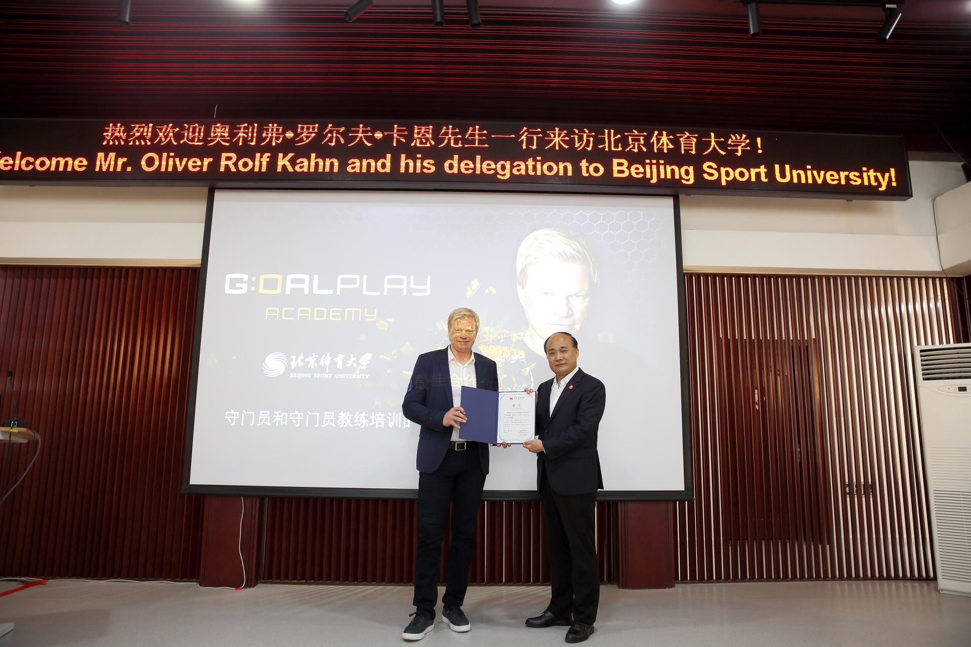 Xia Lunhuo, Vizepräsident der Sportuniversität Peking, überreicht Oliver Kahn seine Urkunde zur Berufung als Gastprofessor. Er soll dem Land auf der Torhüter-Position zu fußballerischer Weltklasse verhelfen.
