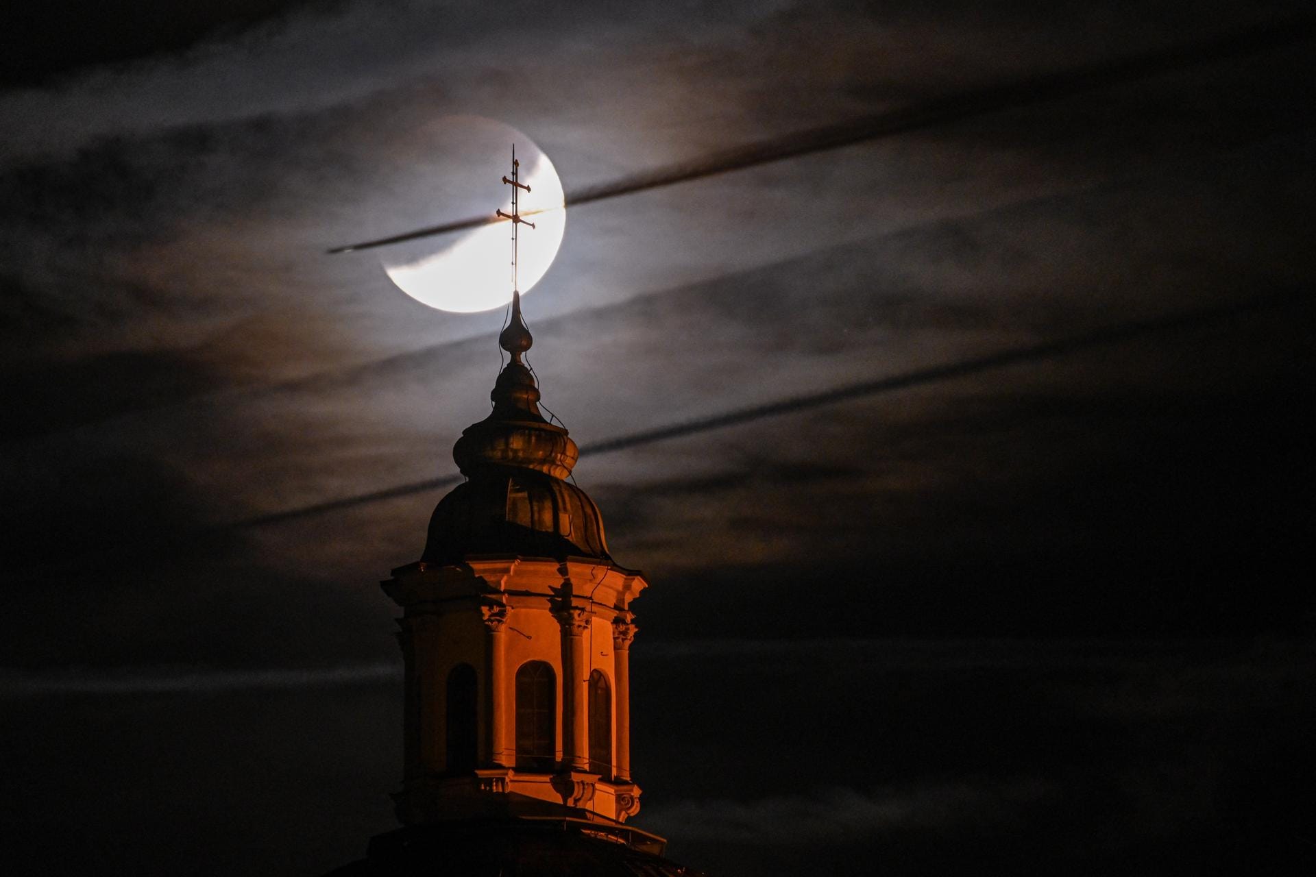 Baden-Württemberg, Weingarten: Der teils verdeckte Mond ist hinter Basilika zu sehen, während ein Flugzeug vor dem Mond vorbei fliegt.