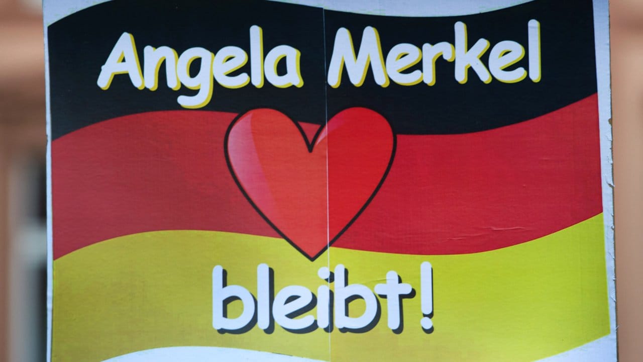Ein Schild mit dem Schriftzug "Angela Merkel bleibt" wird vor dem Rathaus 2016 hochgehalten.