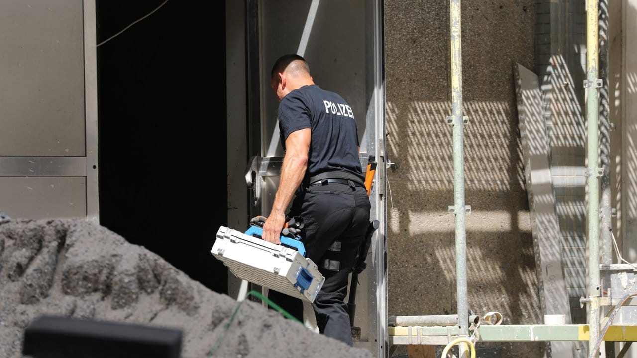 Ein Polizist geht mit einem Koffer in das Wohngebäude in der Kölner Innenstadt.