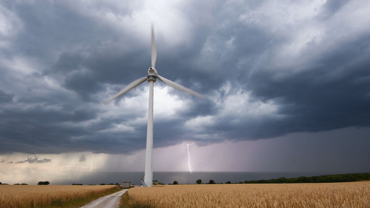 Eine Unwetterfront zieht über ein Feld in der Region Hannover hinweg, als am Horizont ein Blitz einschlägt.