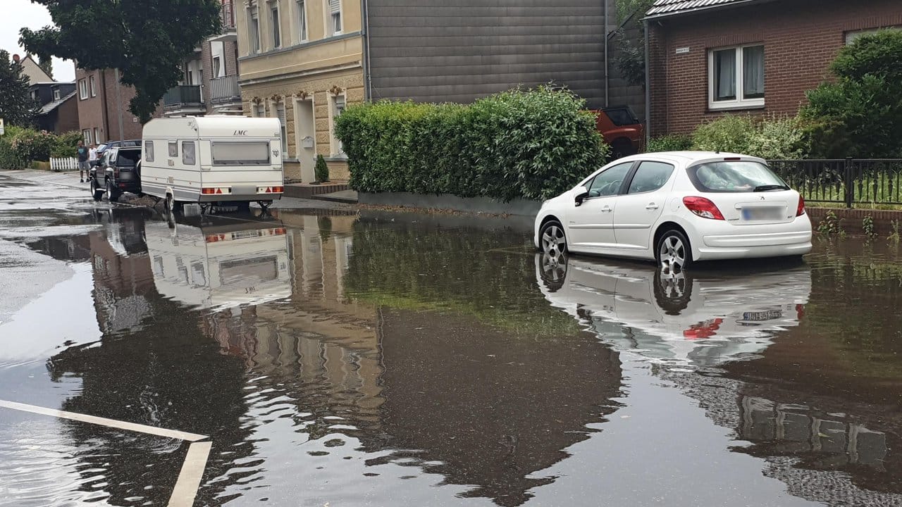 Autos stehen nach Starkregen auf einer überfluteten Straße in Mönchengladbach.