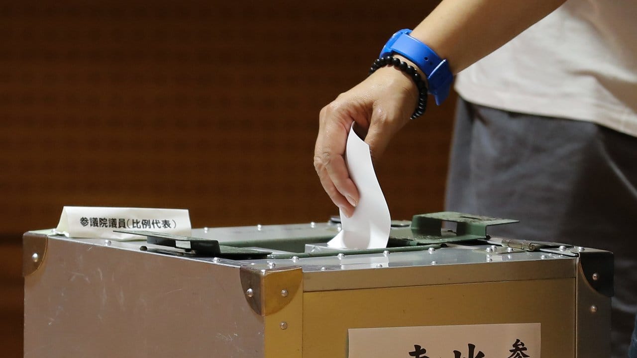 Ein Wähler wirft in einem Wahllokal in Tokio einen Stimmzettel in eine Wahlurne.